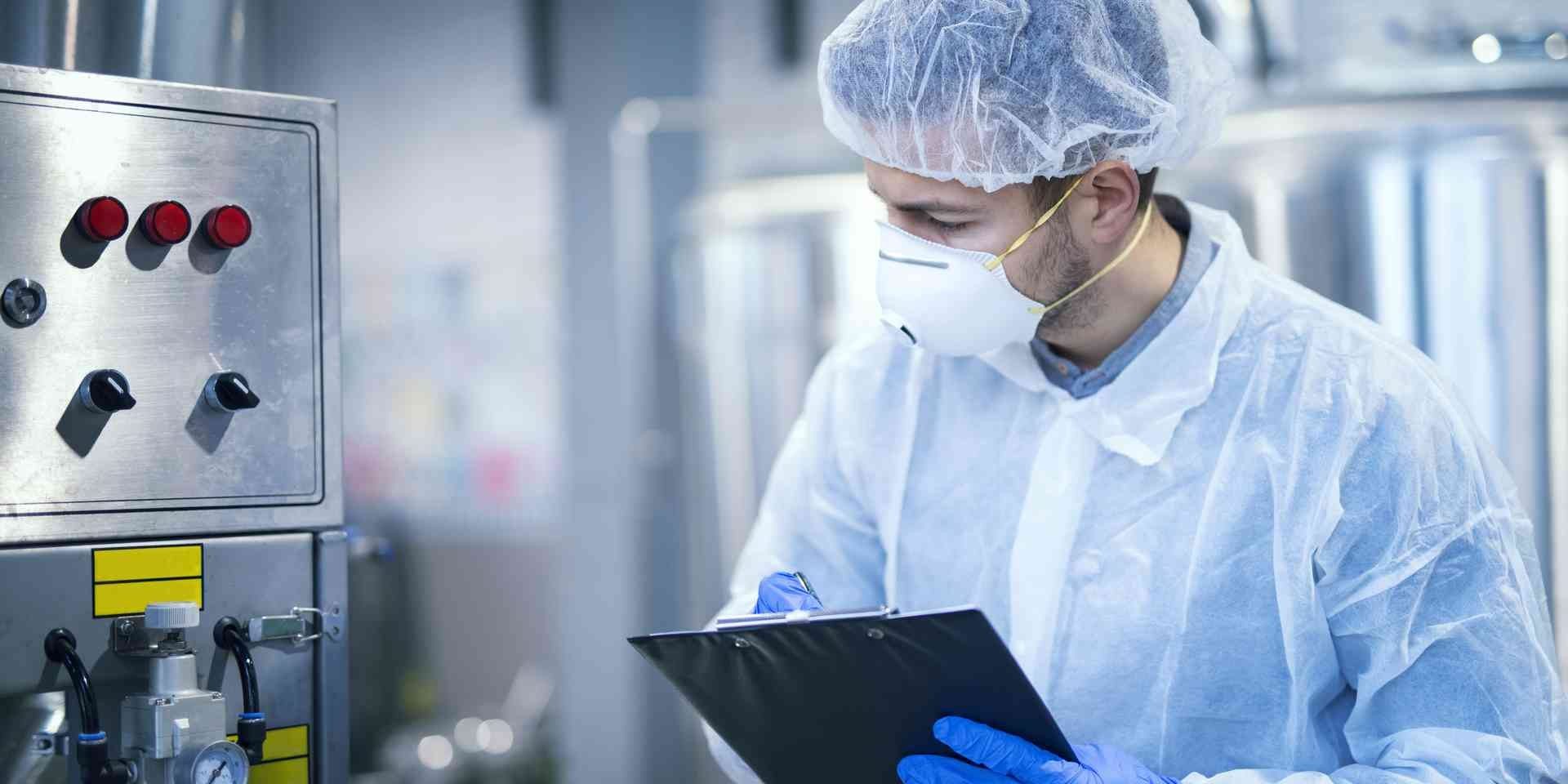 technologist-expert-protective-uniform-with-hairnet-mask-taking-parameters-from-industrial-machine-food-production-plant