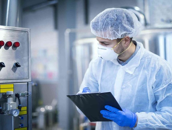technologist-expert-protective-uniform-with-hairnet-mask-taking-parameters-from-industrial-machine-food-production-plant